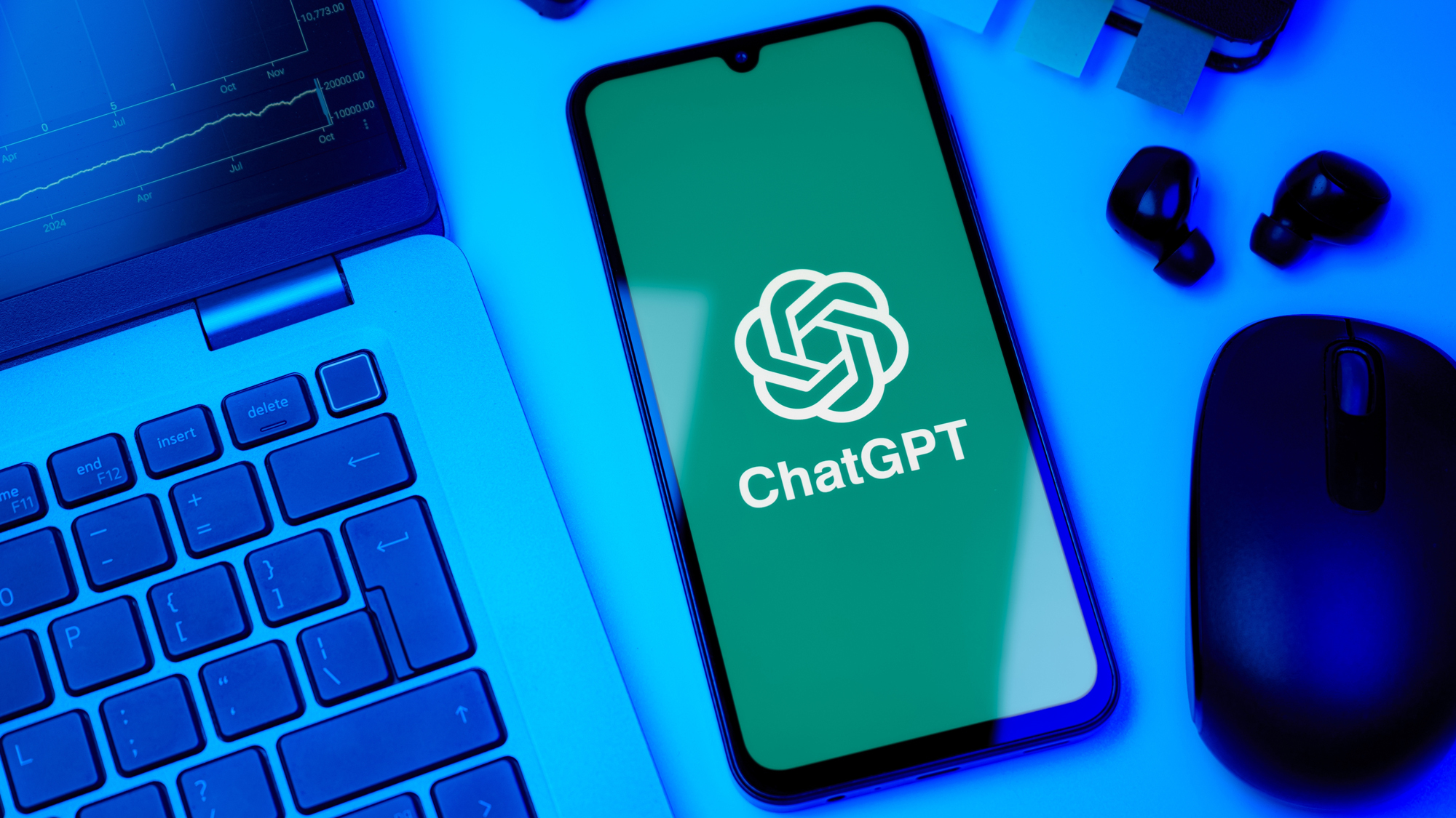 شعار ChatGPT على هاتف ذكي بجوار جهاز كمبيوتر محمول