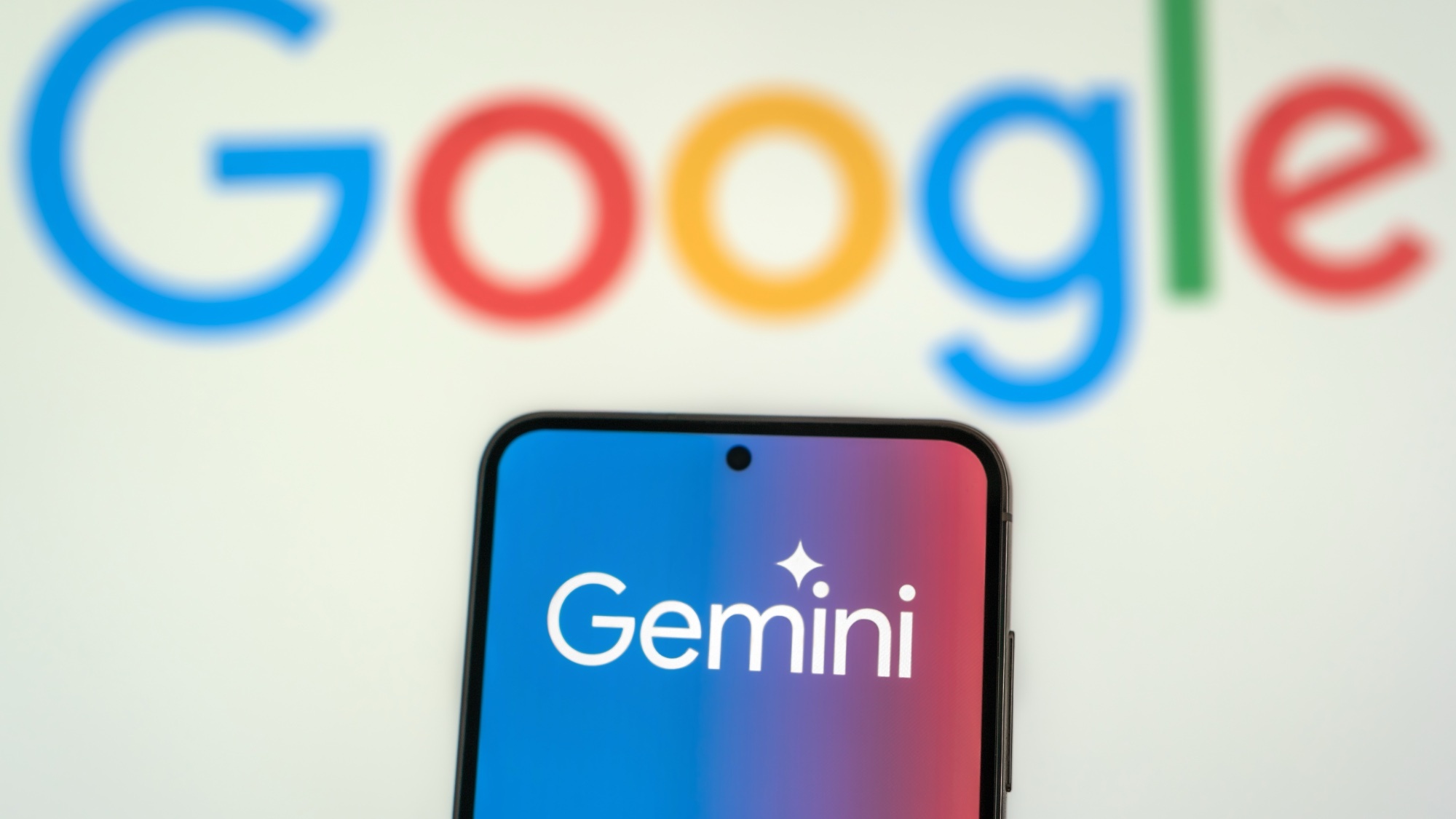 Gemini logo on smartphone with the Google logo behind