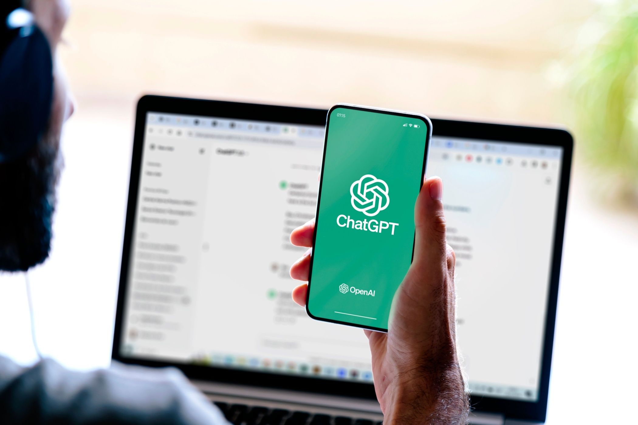 رجل ينظر إلى ChatGPT على هاتف ذكي وجهاز كمبيوتر