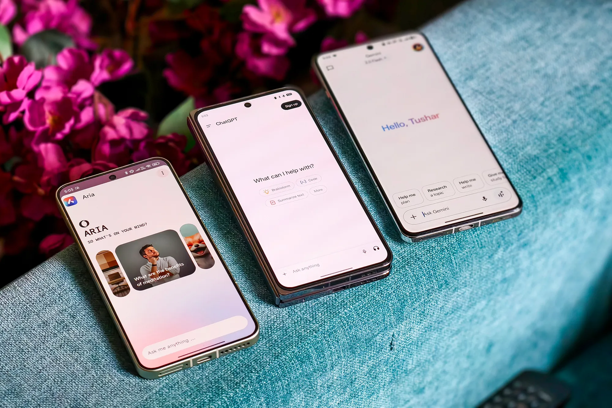 Opera Mini Aria AI chatbot vs ChatGPT and Google Gemini running on Android phones resting on a blue fabric sofa.