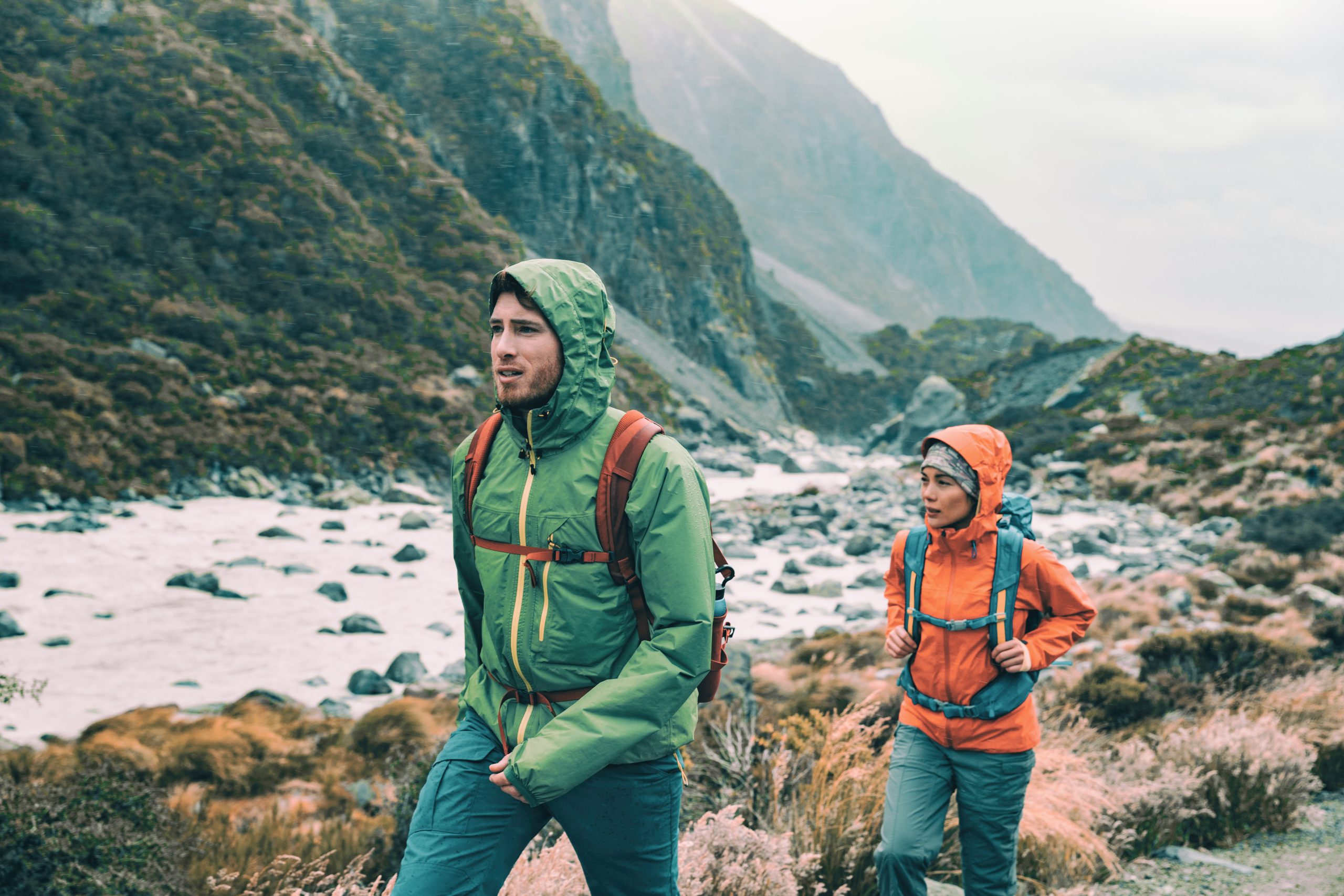 a photo of a man and woman hiking with the hoods up on their waterproof jackets