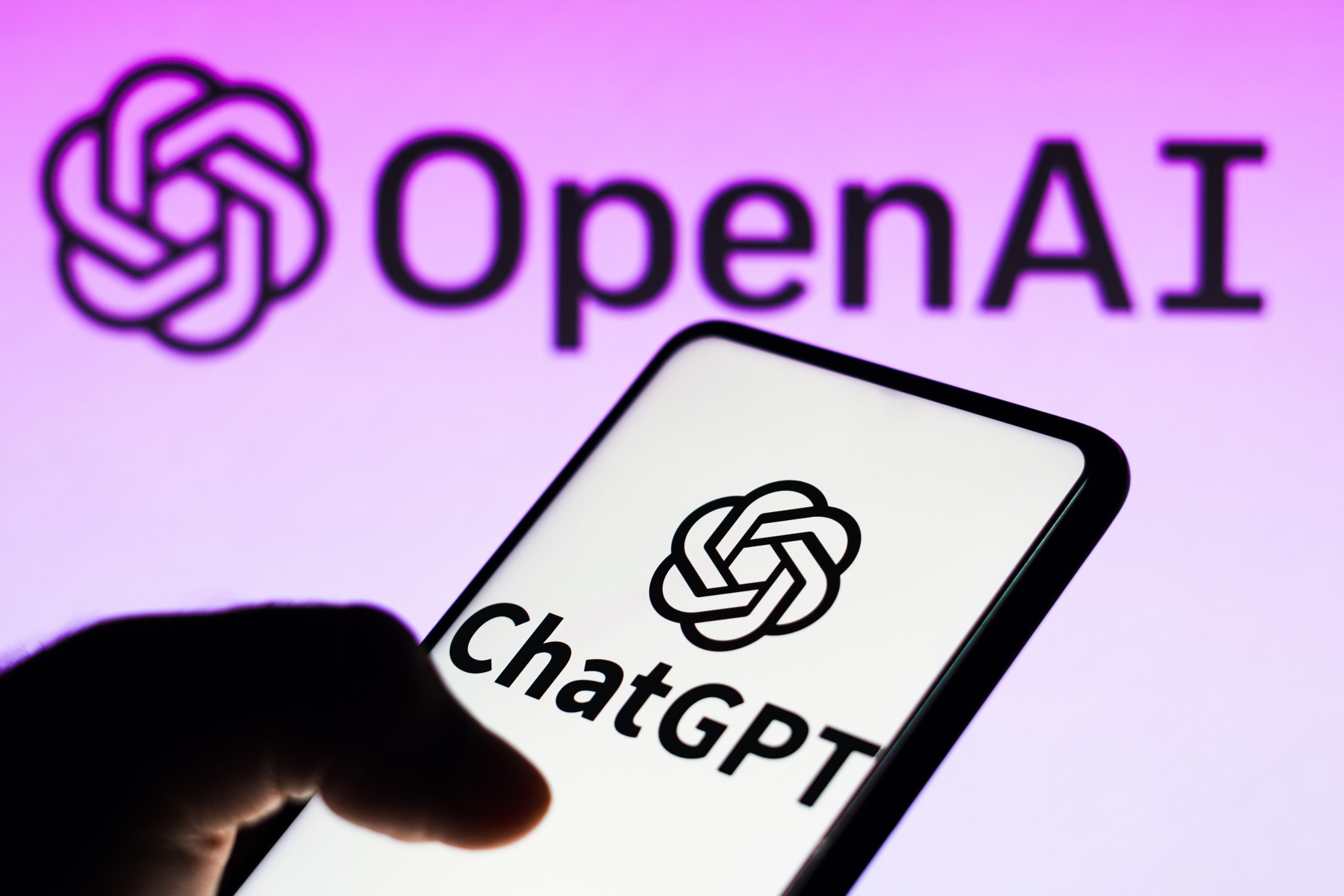 شعار ChatGPT على هاتف ذكي مع علامة OpenAI في الخلفية