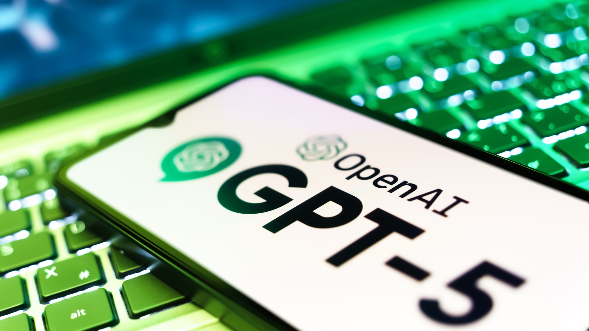 ChatGPT-5 logo on phone resting on laptop keyboard 