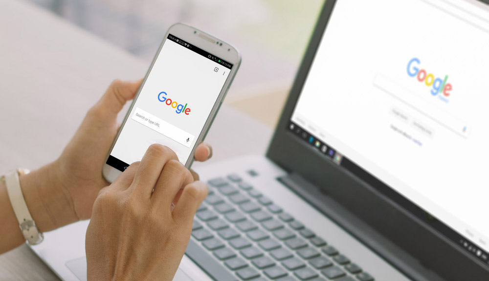 امرأة تبحث في Google Search على هاتف ذكي وجهاز كمبيوتر محمول.