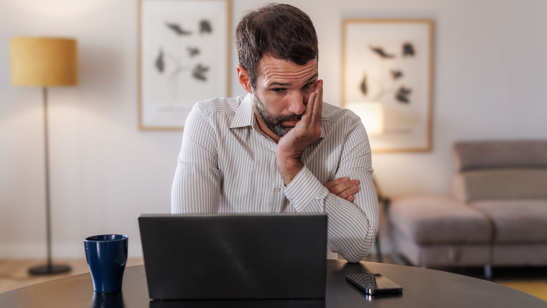 رجل ينظر إلى حاسوبه المحمول بأسلوب متوتر ومنزعج