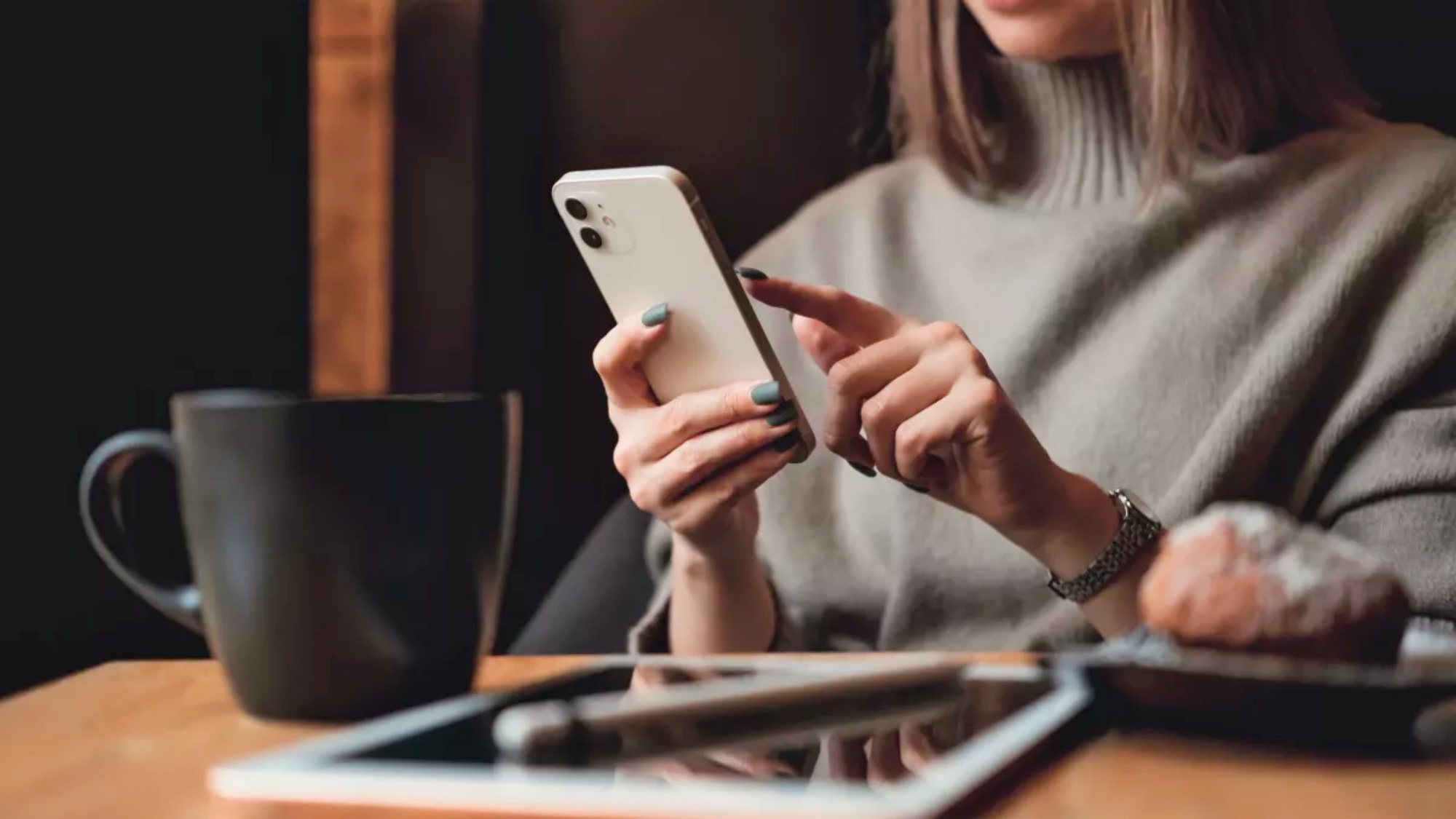 Kobieta trzymająca iPhone'a w pobliżu iPada