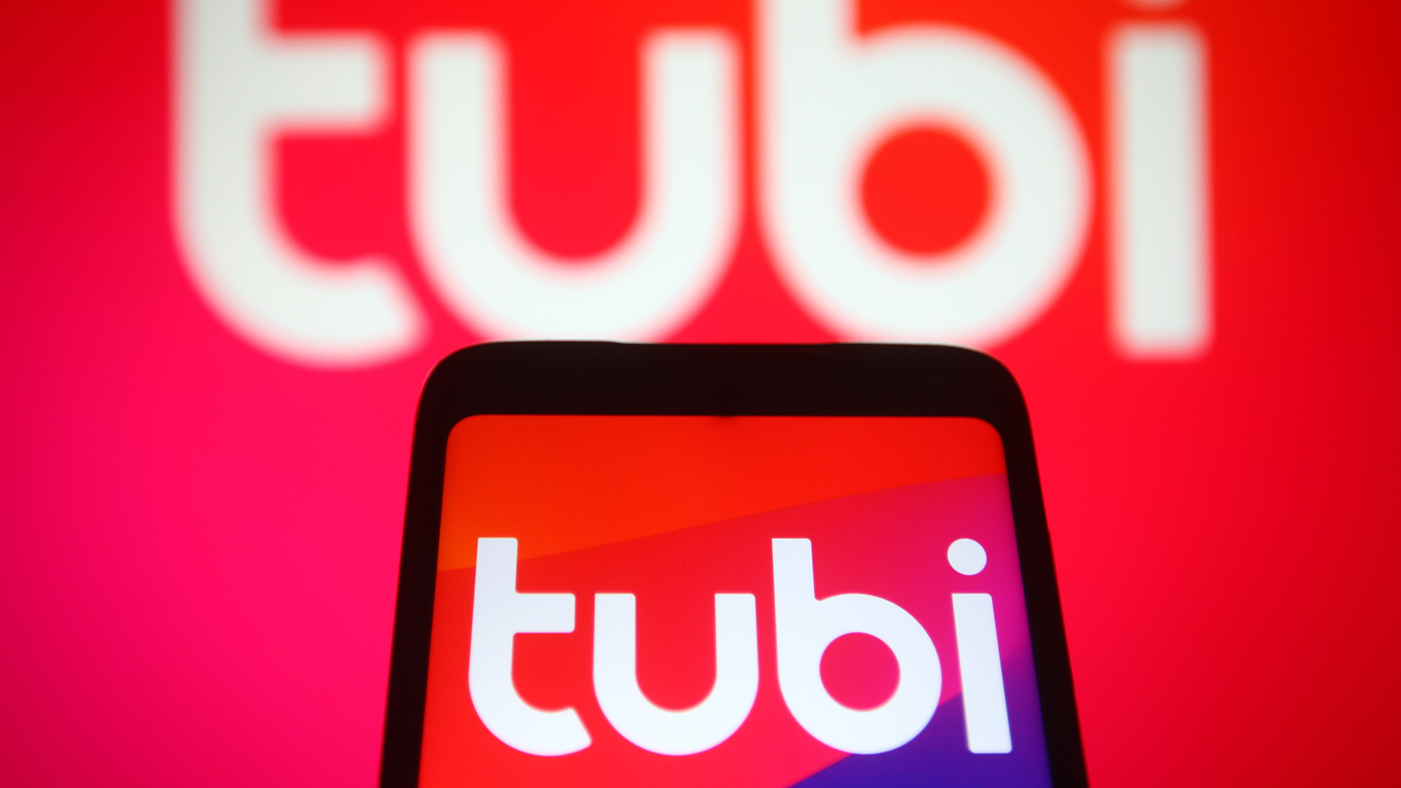 شعار Tubi على هاتف أمام شعار Tubi على شاشة أكبر
