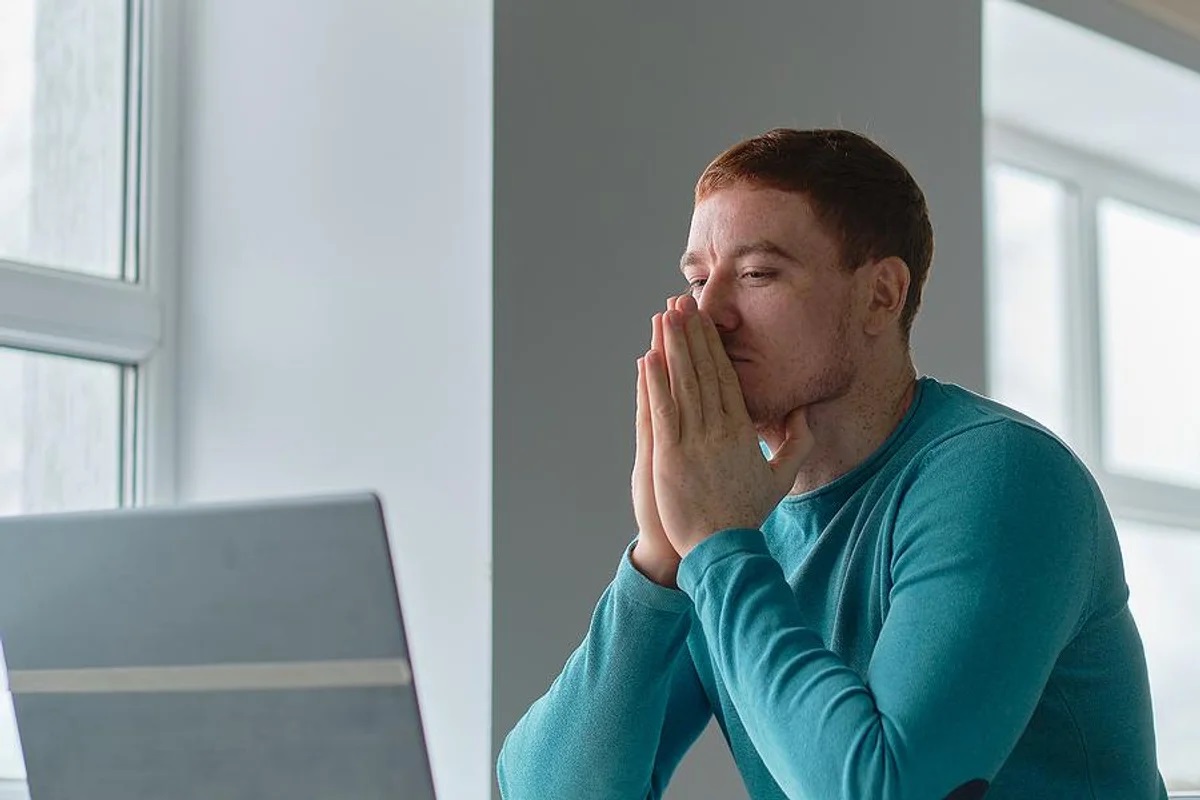 رجل يستخدم جهاز كمبيوتر محمول ويكافح لكتابة سيرته الذاتية بعد فصله من العمل