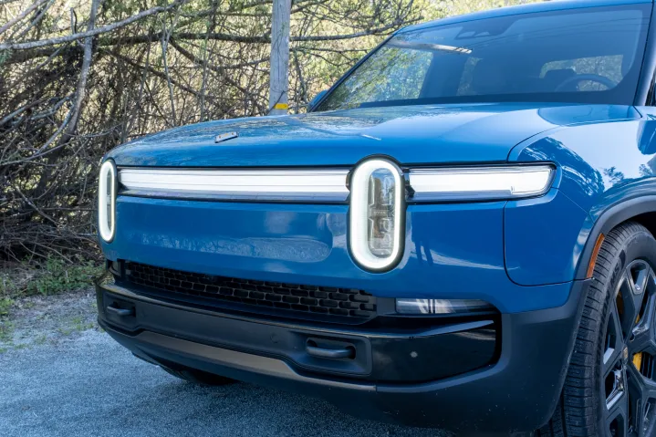 The headlights of a blue 2025 Rivian R1T truck