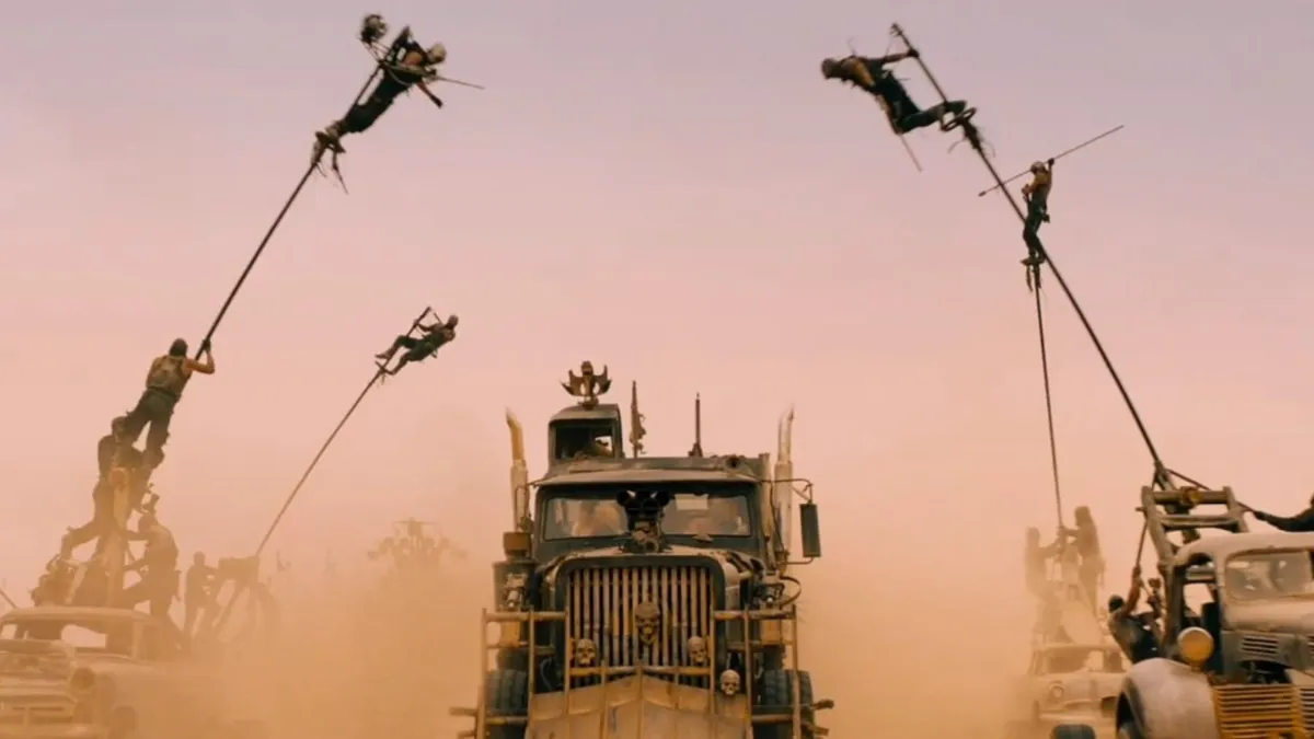 Men swing from poles while driving cars in the desert in "Mad Max: Fury Road."