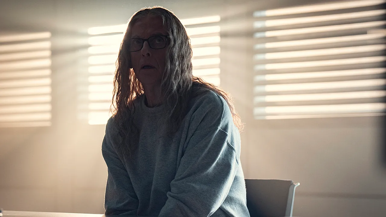 An older man with long hair sitting in an interrogation room in Black Mirror.