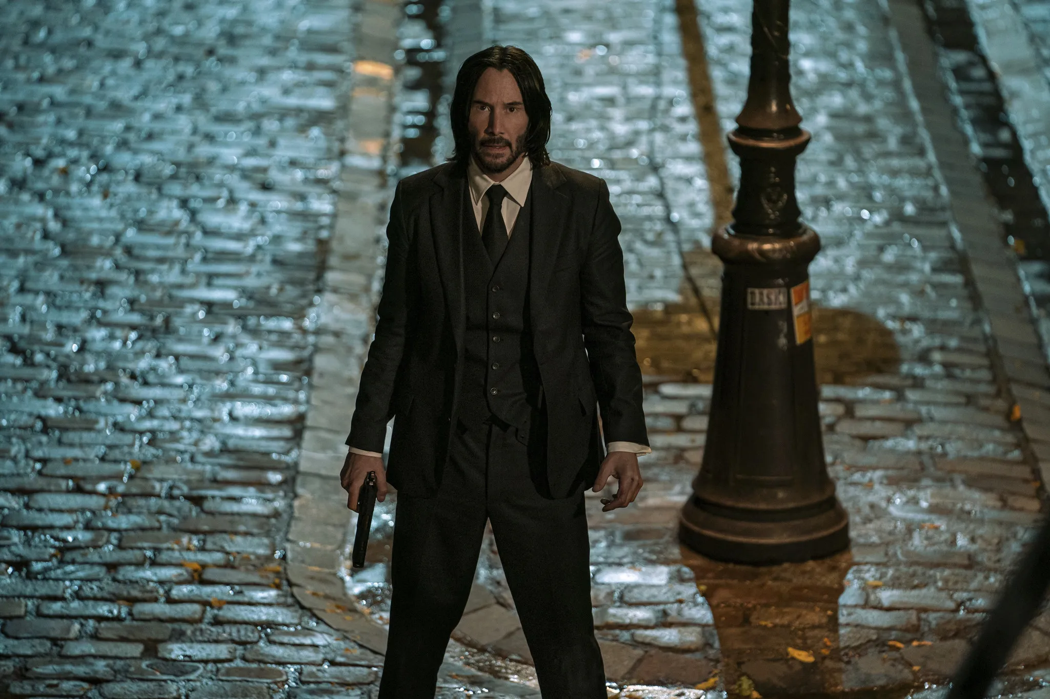 John Wick stands at the bottom of the stairs in "John Wick: Chapter 4."
