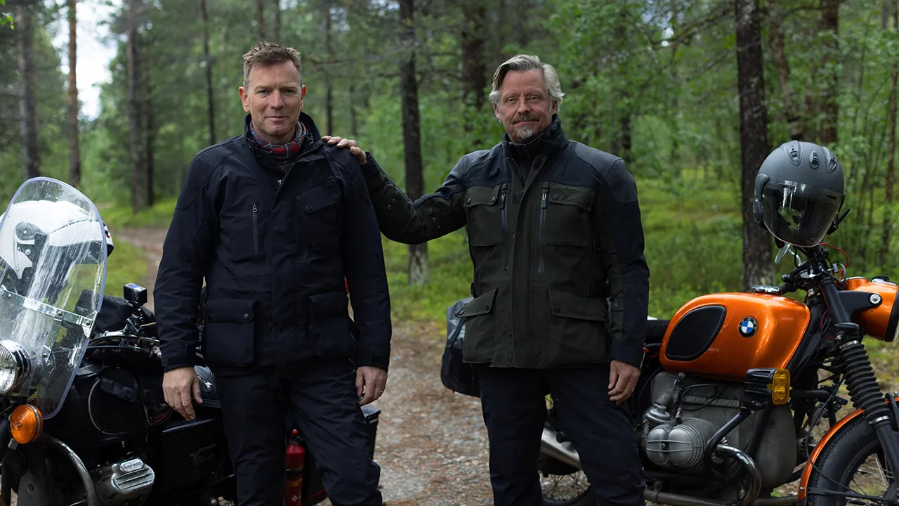 Two men pose beside their motorcycles in Long Way Home on Apple TV+.