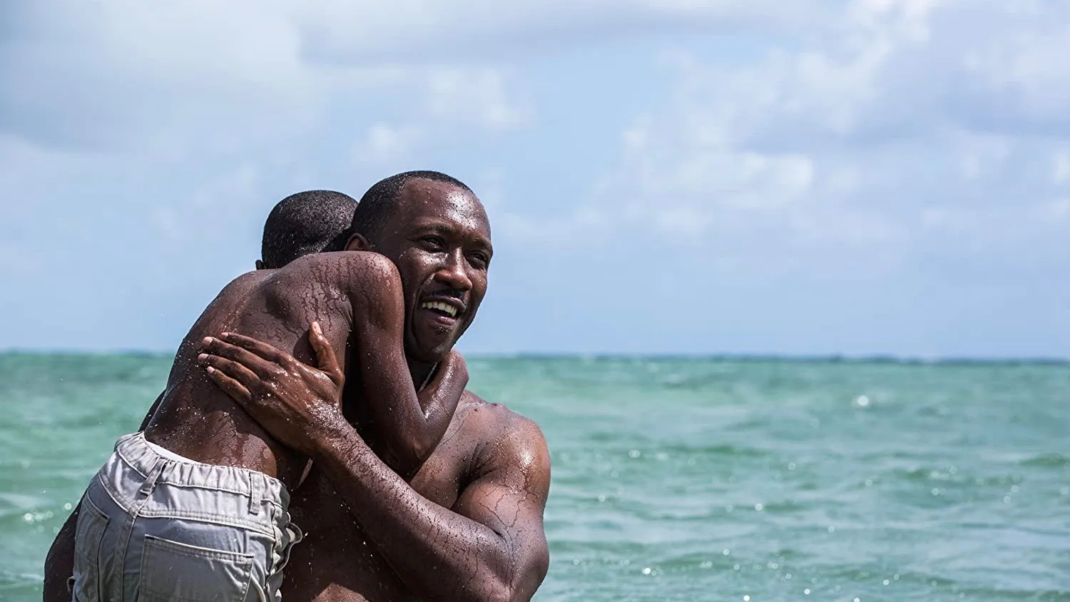 Mahershala Ali cradles a child in the water in a still image from the movie Moonlight.