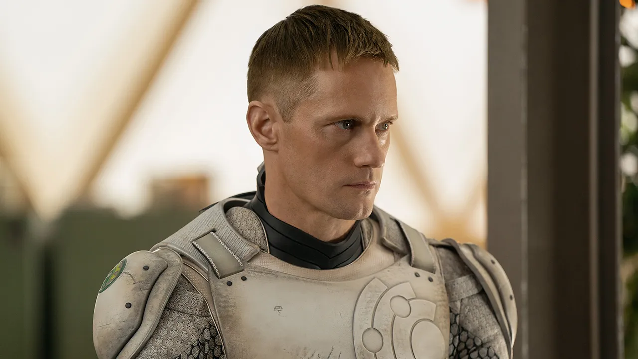 Alexander Skarsgard wearing a robot uniform and looking serious in Murderbot.