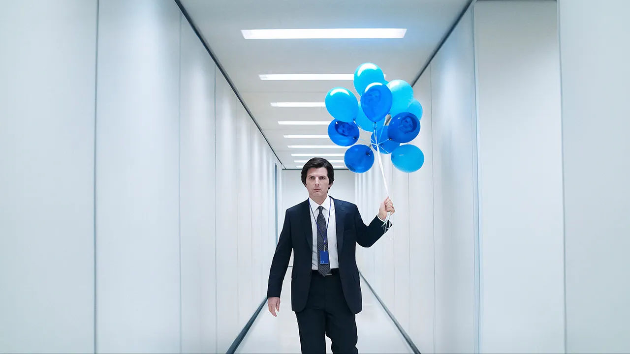 Mark walking down a bright, white hallway with blue balloons in Severance.