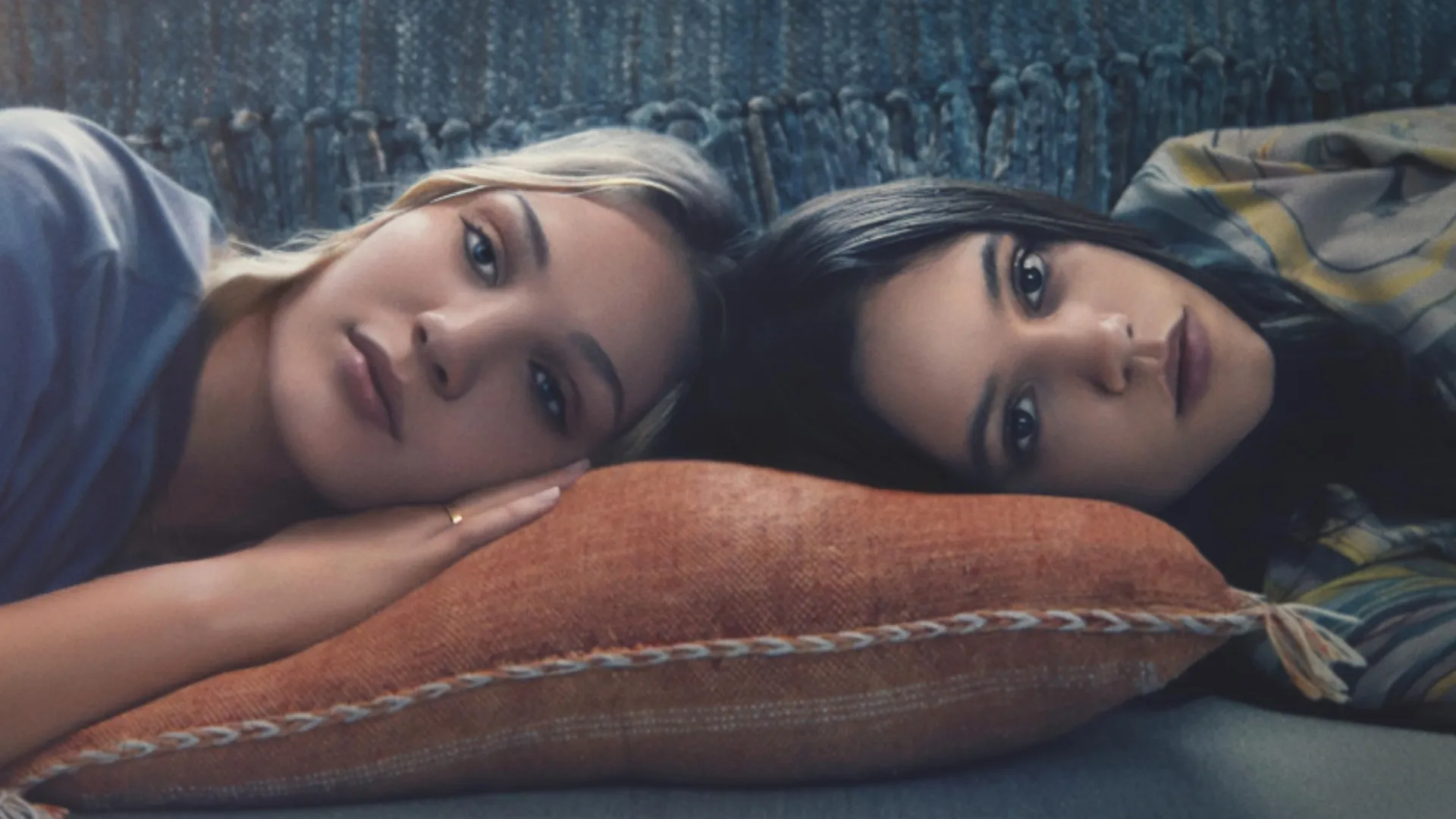 Two girls lie down on the couch.