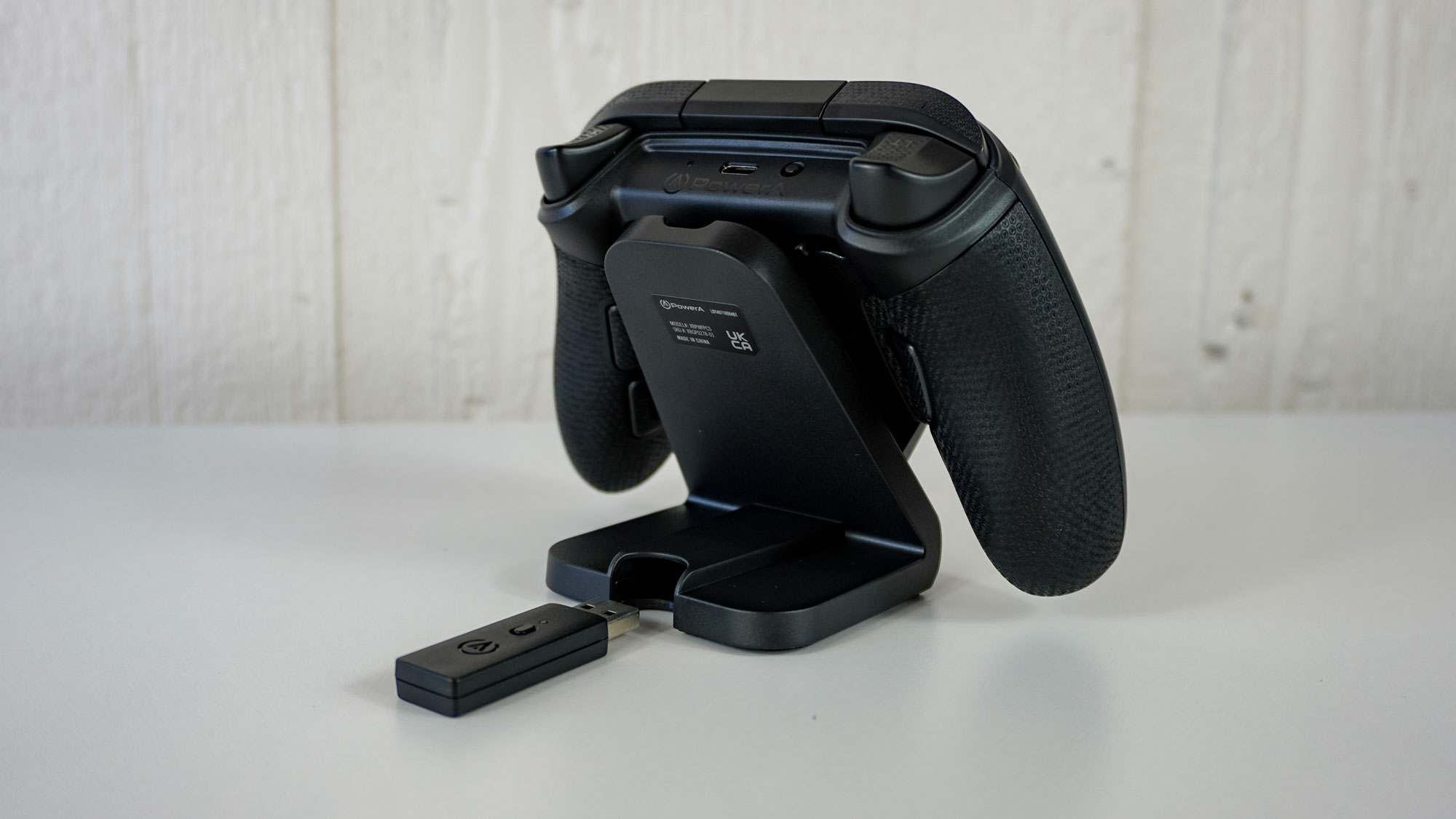 A rear shot of the PowerA Fusion Pro Wireless Controller on its magnetic charging stand showing the storage compartment for its wireless adapter