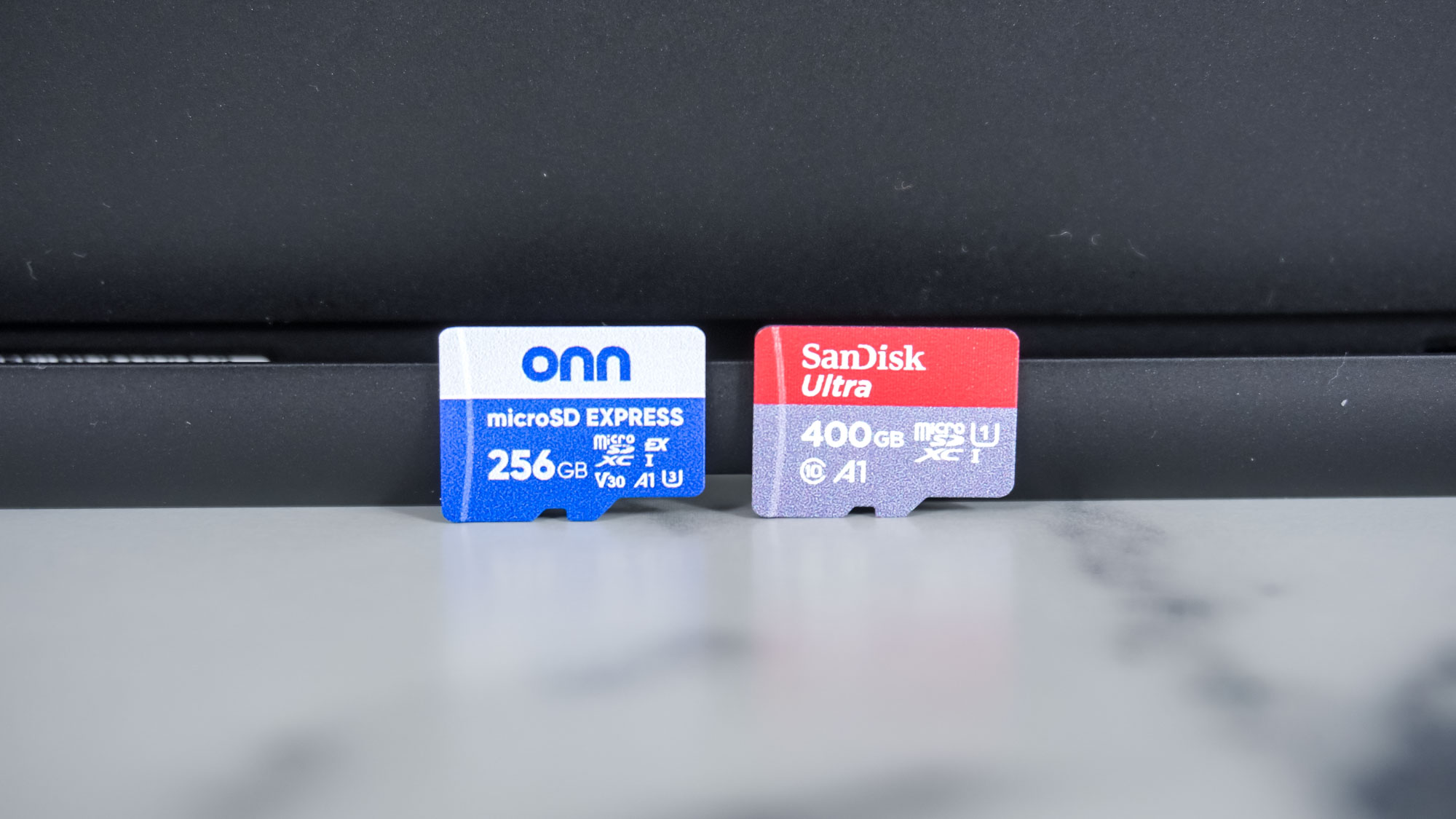 An Onn microSD Express card side by side with a SanDisk microSD card leaning on the Nintendo Switch 2's kickstand