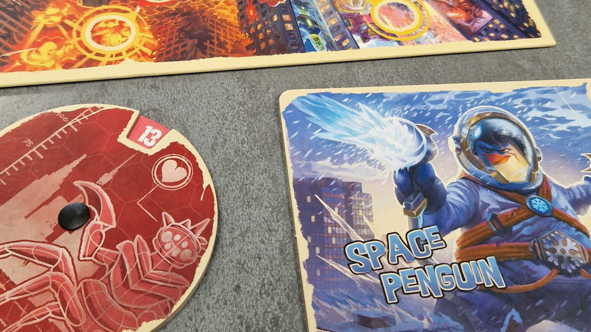 لوحة لعب King of Tokyo: Duel Space Penguin مع عداد حياة ولوحة بجانبها