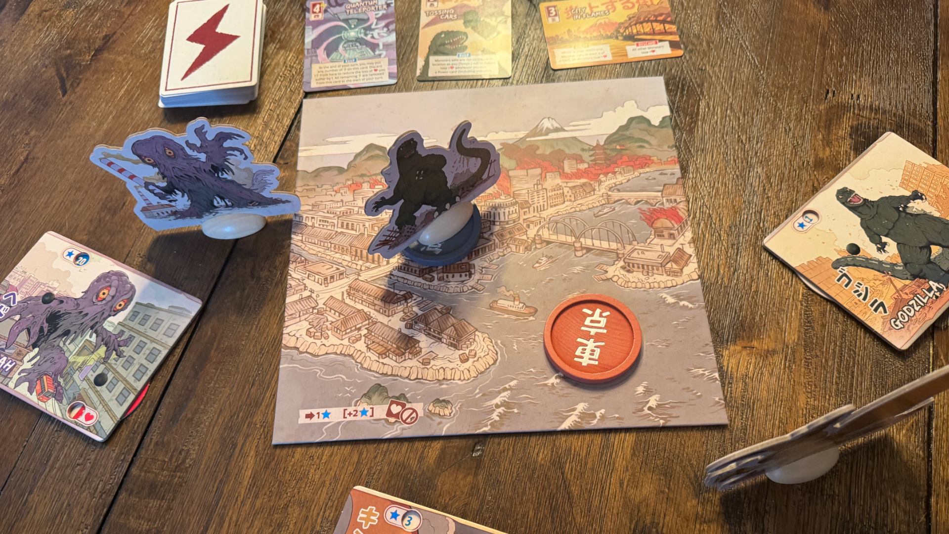 لوحة لعبة King of Tokyo: Godzilla، بطاقات، ورموز على سطح خشبي