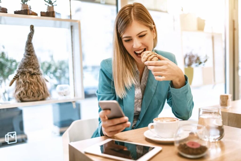 امرأة تتناول الطعام بينما تستخدم هاتفها للعمل
