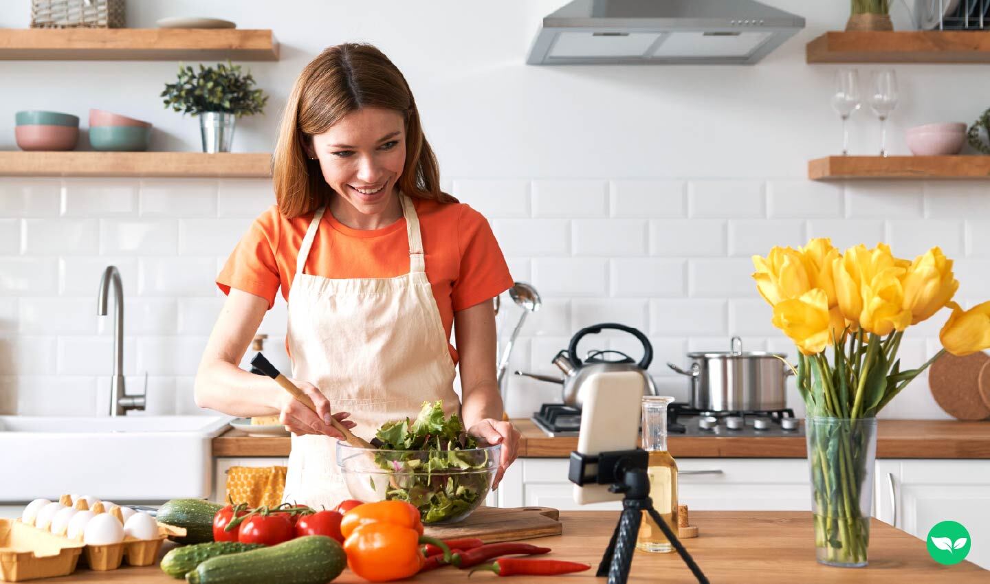 Una donna registra un video di cucina nella sua cucina, a dimostrazione della creazione di contenuti su YouTube.