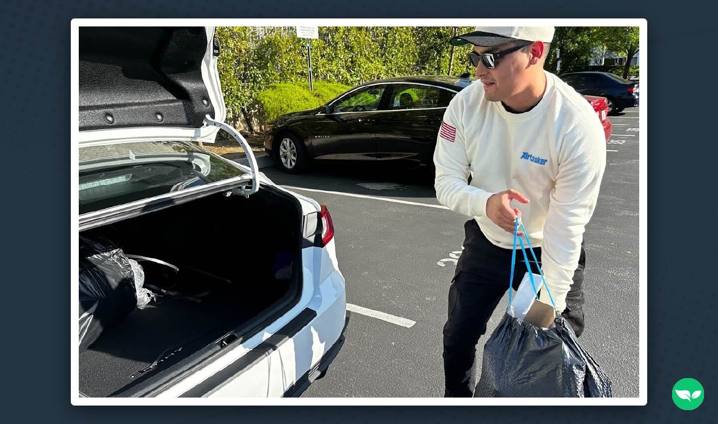 Martin de Anda carica i sacchi delle consegne nel bagagliaio della sua auto mentre indossa l'uniforme di Airtasker.