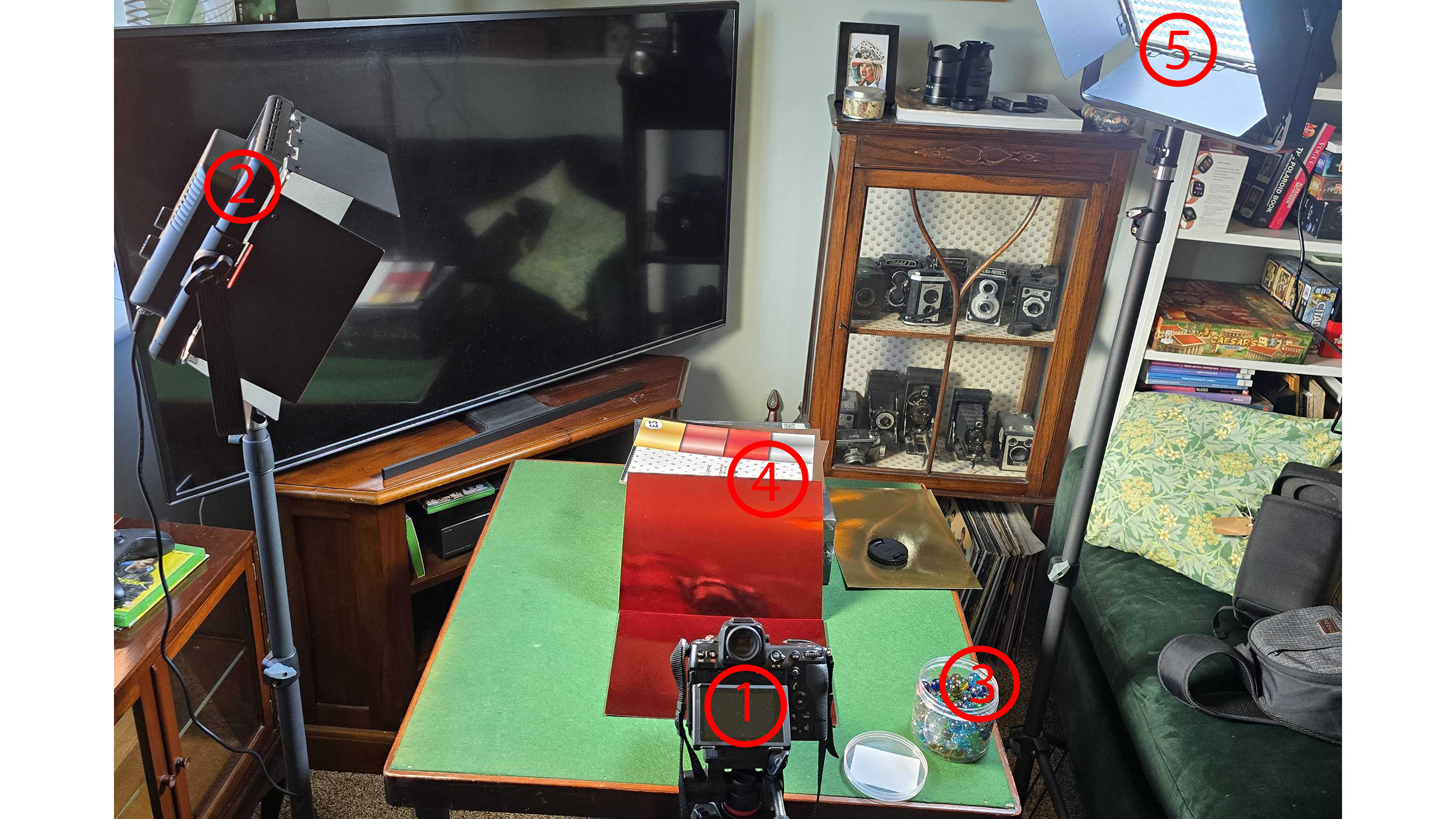 Twee lampen, een tafel, een camera, een rode kaart en glazen knikkers.