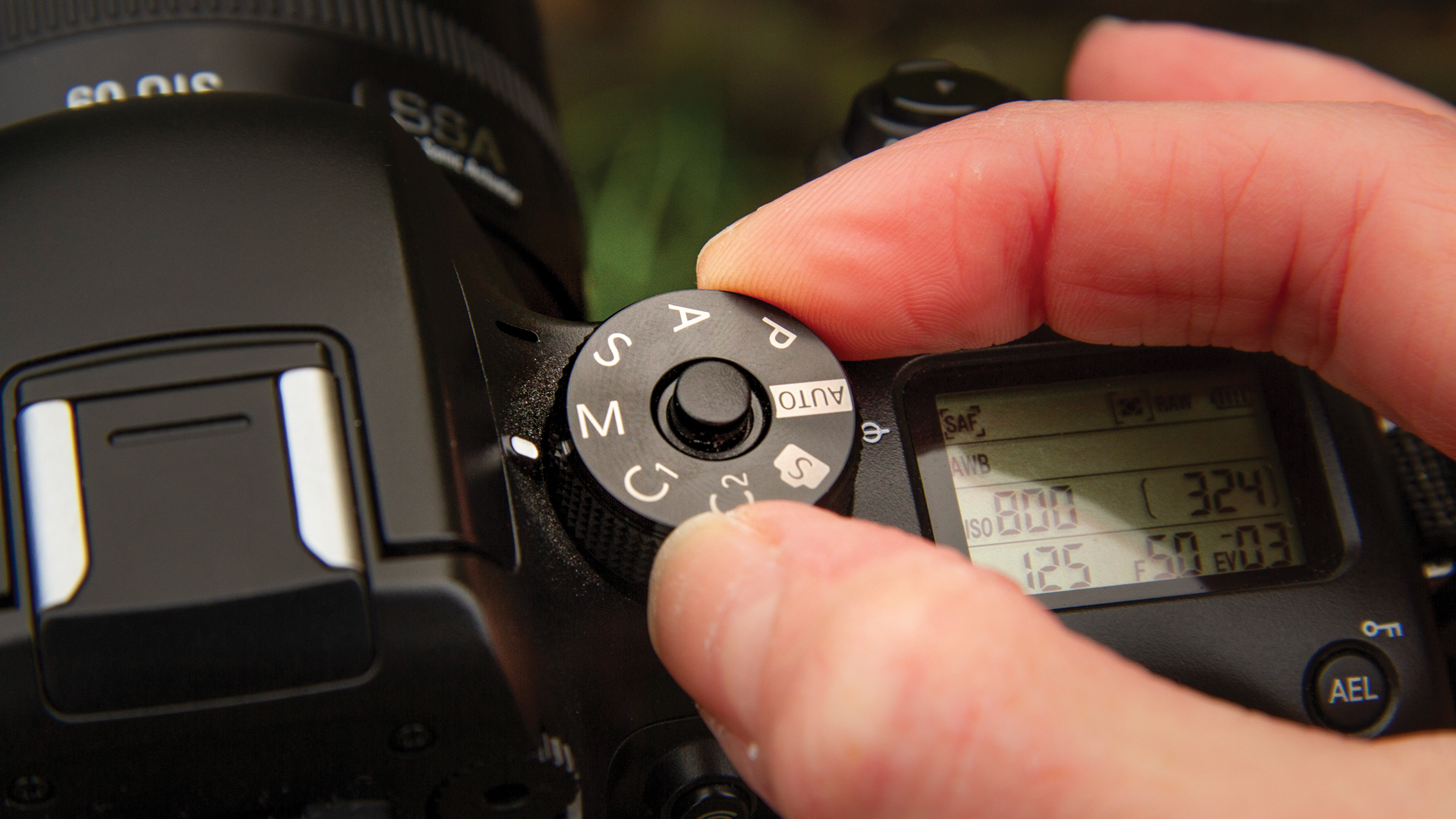يد تقوم بضبط قرص الوضع على كاميرا DSLR مضبوطة على أوضاع تصوير مختلفة مع إعدادات عرض الكاميرا المرئية