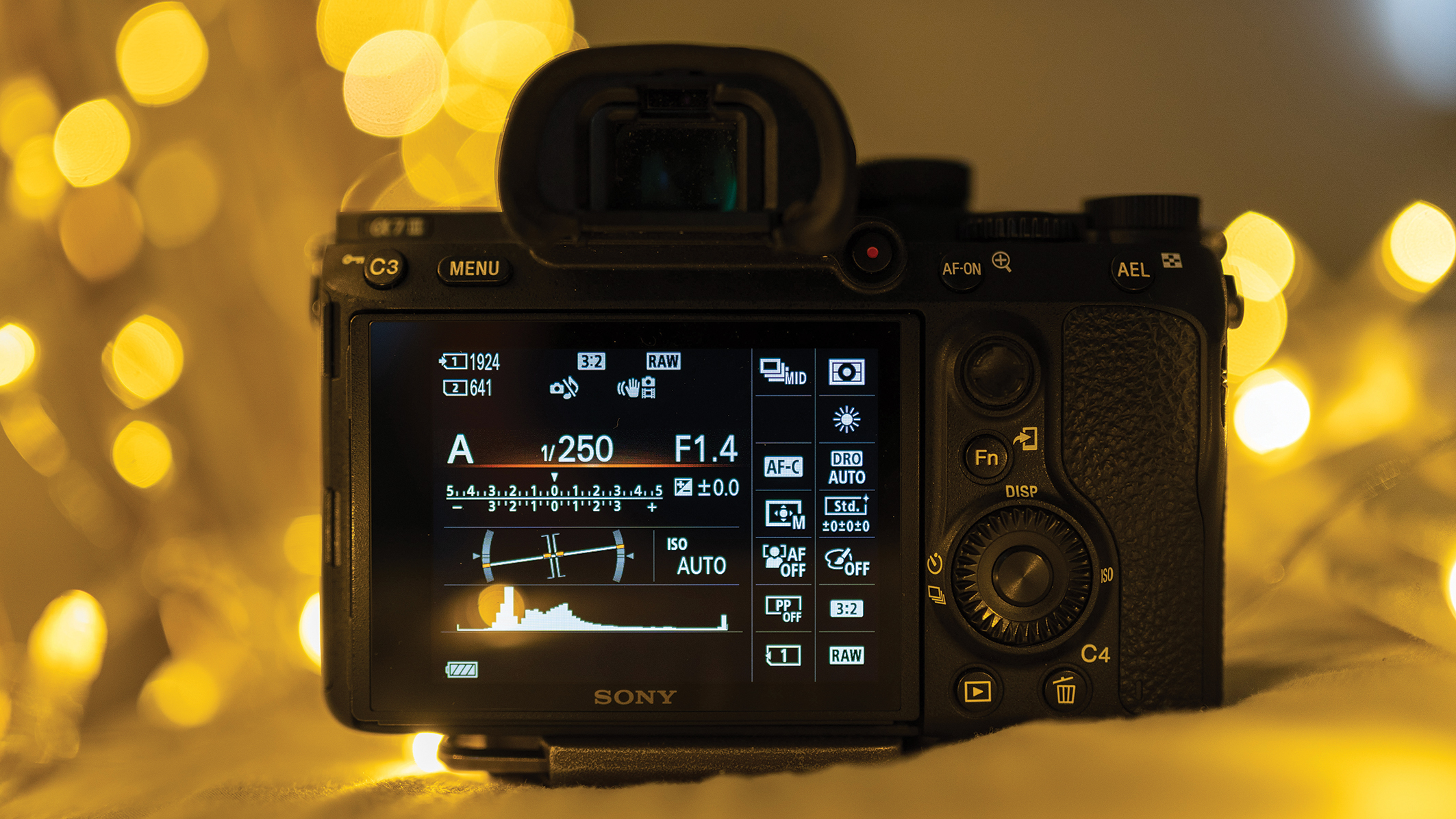 لقطة مقربة لظهر كاميرا رقمية تعرض إعدادات مثل aperture و ISO على شاشتها. أضواء بوكيه دافئة ومضببة تخلق أجواءً مريحة.