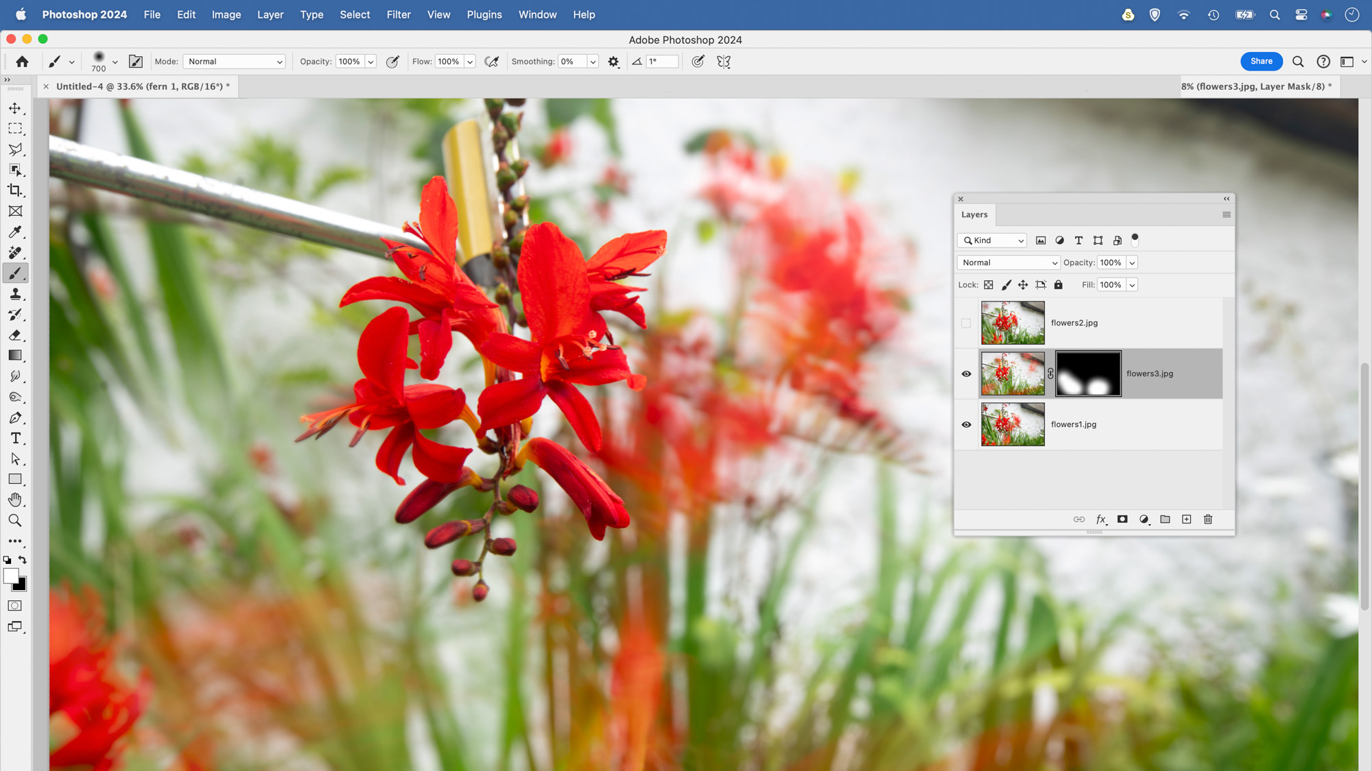 في لقطة الشاشة هذه من Photoshop CC، استخدم المستخدم قناع طبقة لإخفاء أجزاء من صورة زهرة لدمجها مع صورة زهرة أخرى في الطبقة السفلية