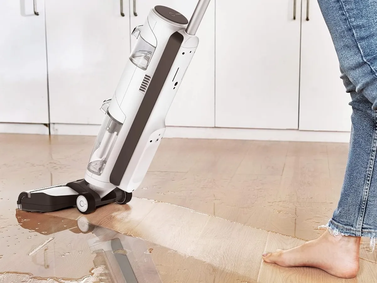 Pushing the Tineco iFLOOR 3 Breeze vacuum across a wet hardwood floor.