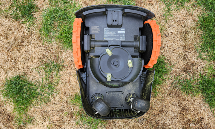 Underside of a Segway Navimow i110 robot lawn mower showing the three blades and a small compartment cover that must be opened to install the optional Access+ module.