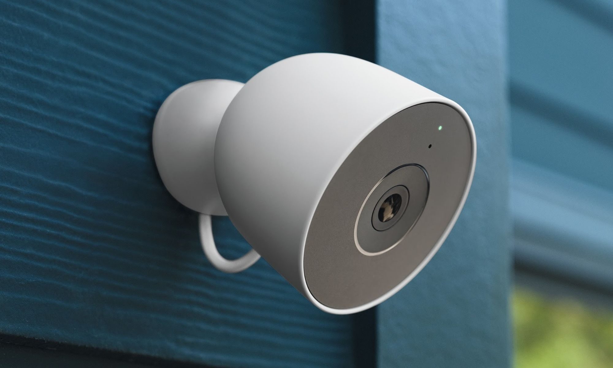 Cámara de seguridad con cable Google Nest Cam Outdoor montada en una pared azul.