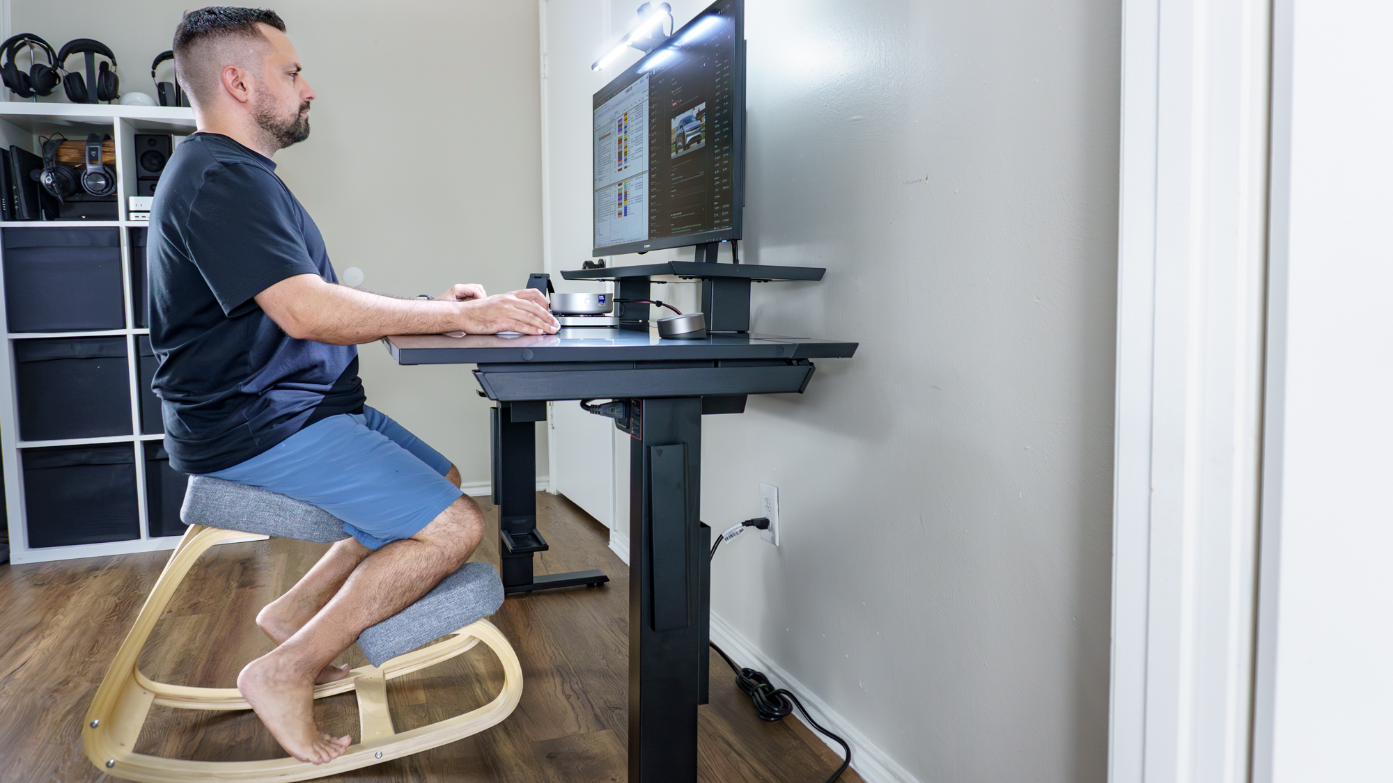 Una persona trabajando en su escritorio sentada en una silla de rodillas.