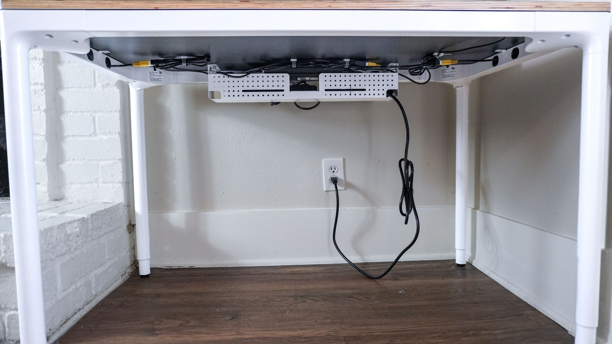 منظر من أسفل المكتب يظهر مكتب Branch Four Leg Standing Desk ومنظم الكابلات الاختياري الخاص به