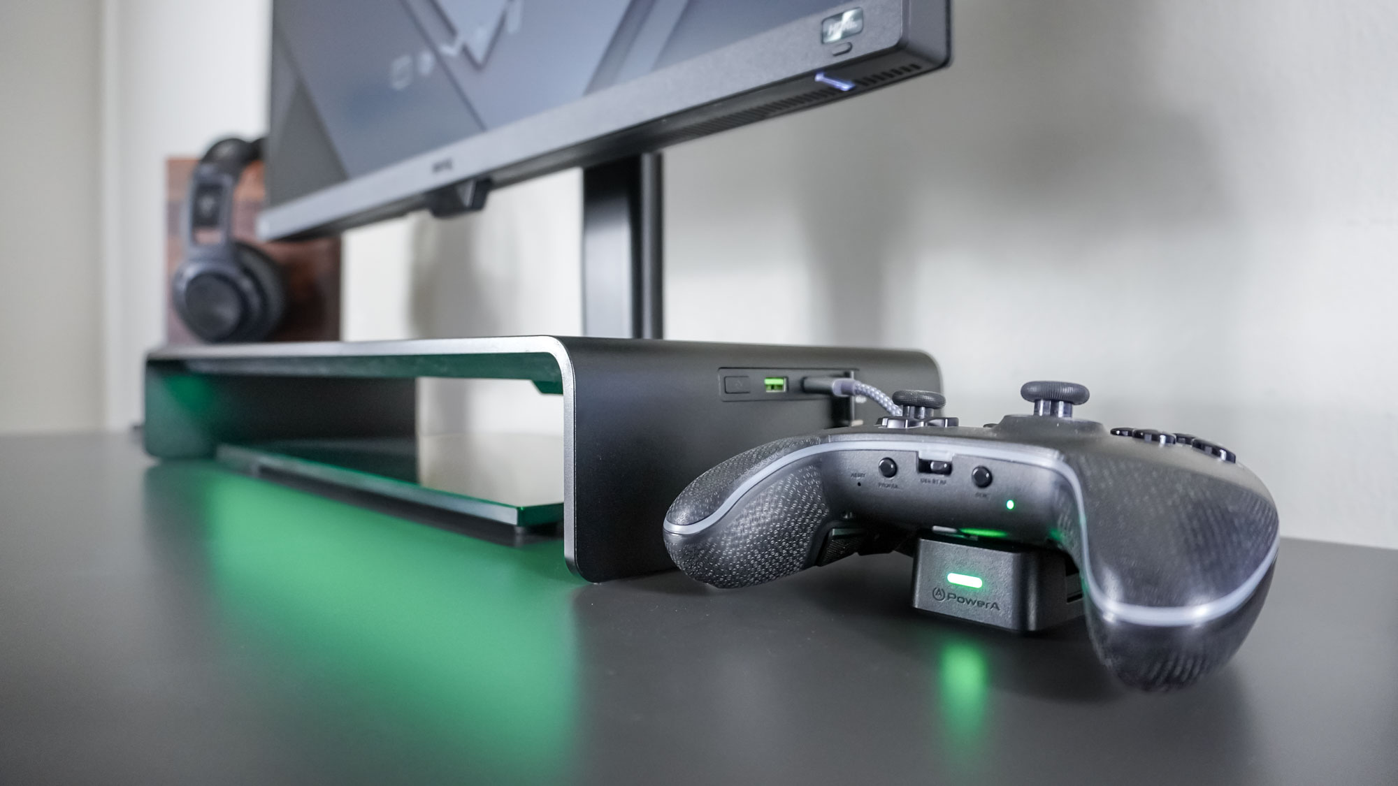 منظر جانبي لحامل شاشة Razer Monitor Stand Chroma في إعداد مكتب مع وحدة تحكم موصولة