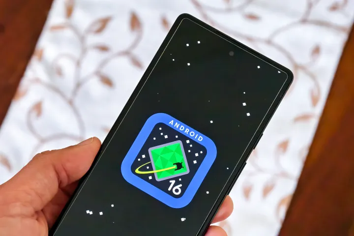 Android 16 logo on Google Pixel 6a held in hand.