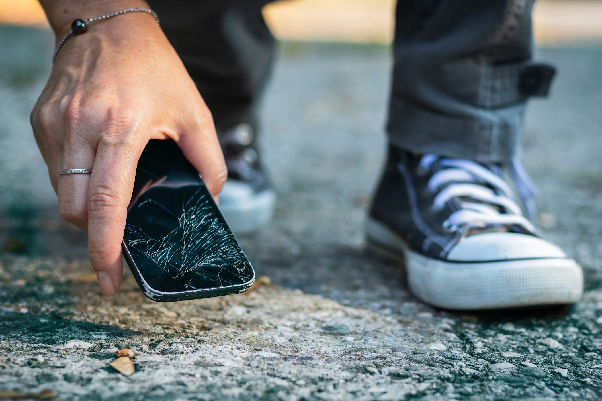A man grabbing a phone he dropped on the ground