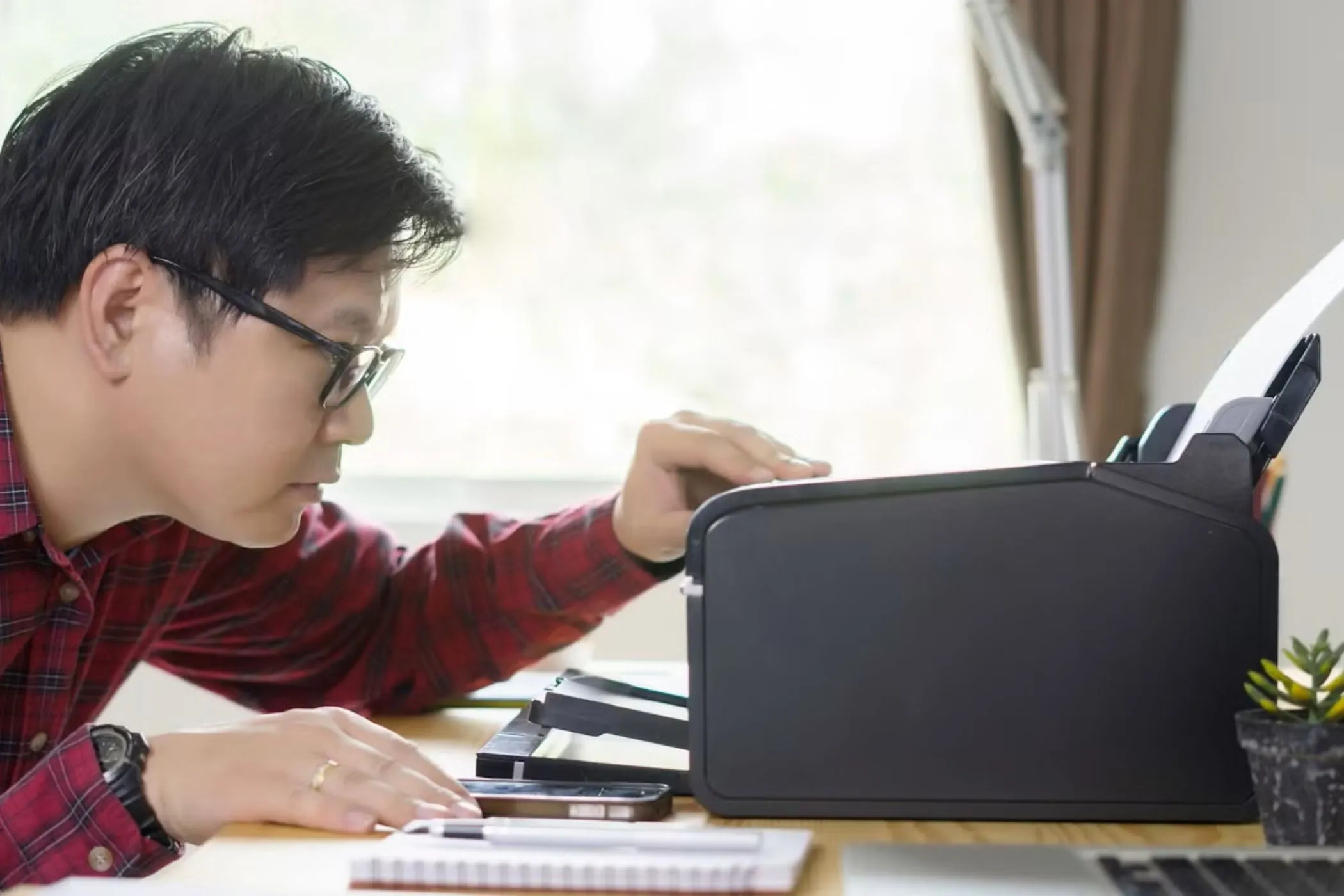 Man looking at printer on a desk.