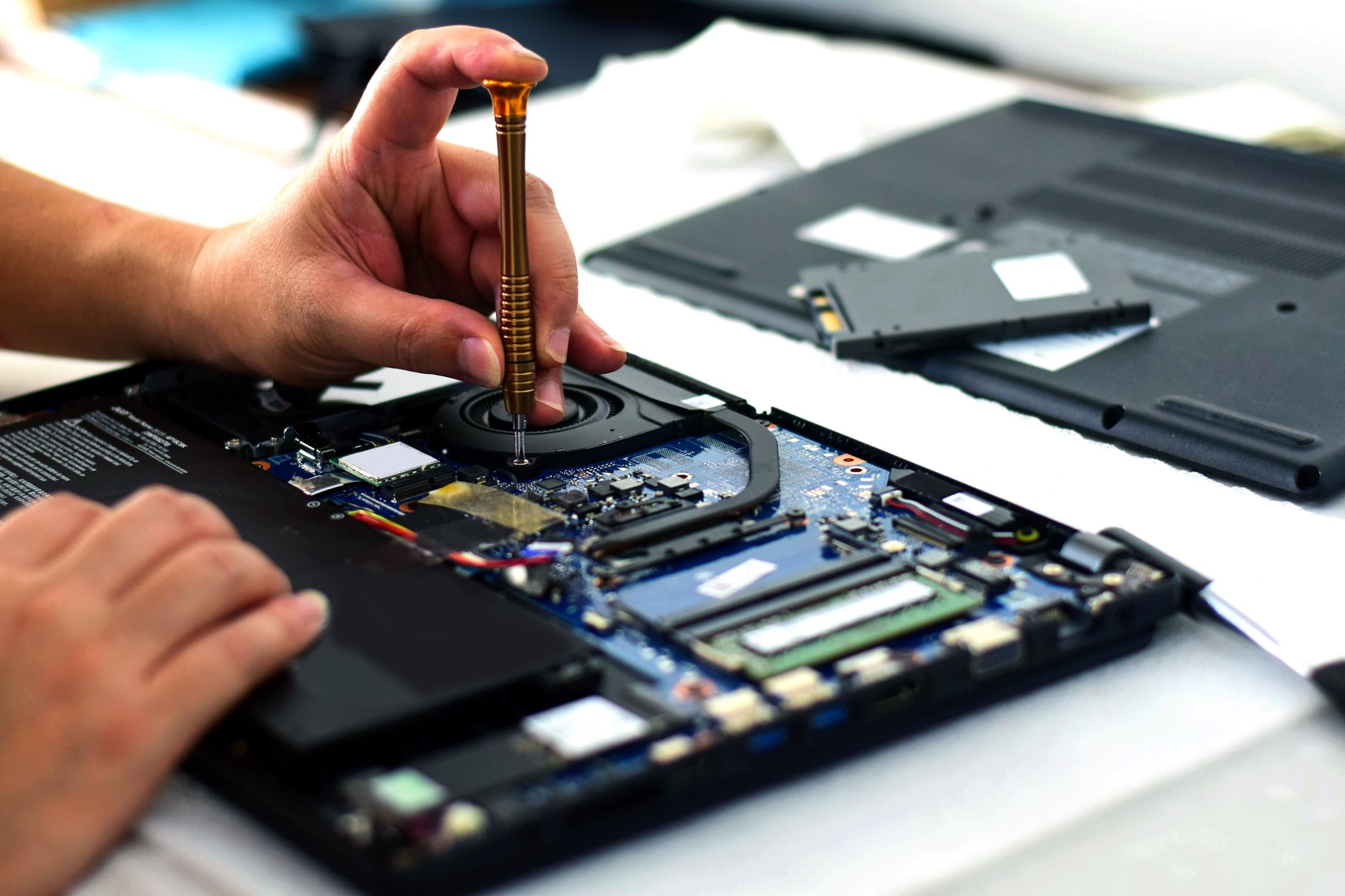 person fixing a laptop motherboard with screwdriver