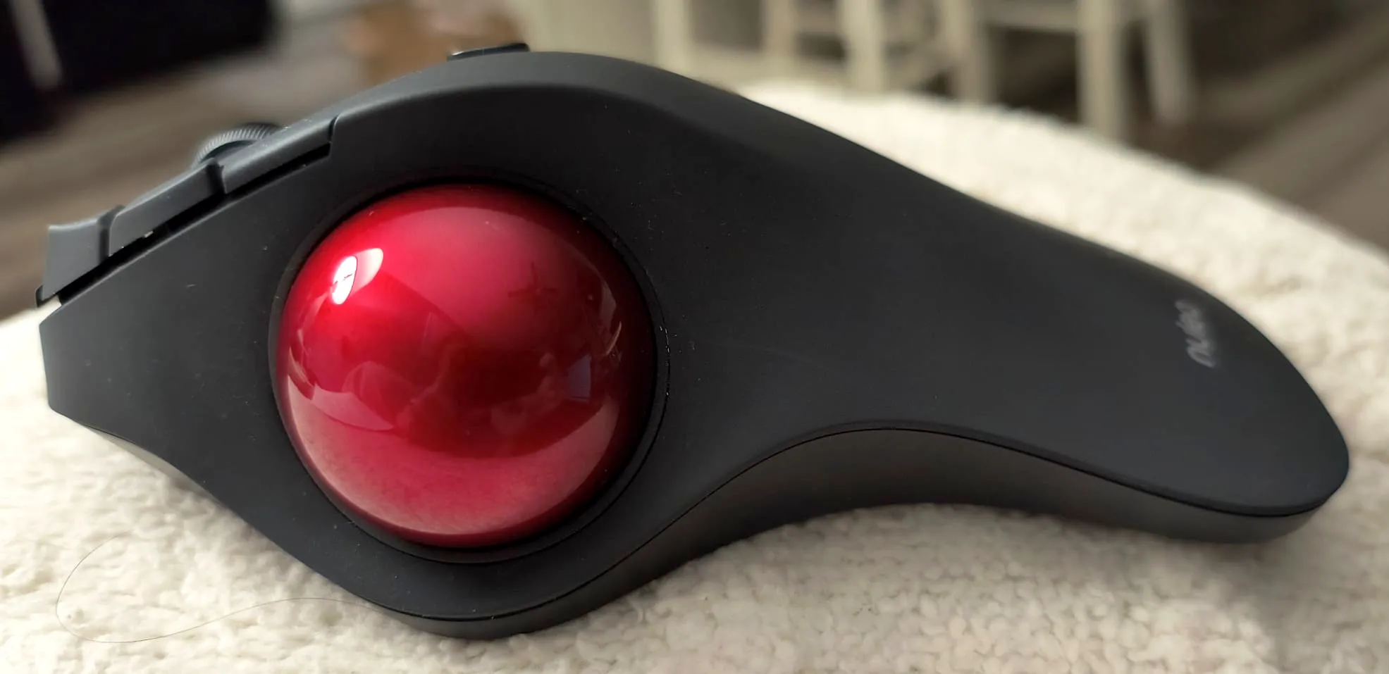 Profile view of a trackball sitting on a white surface.