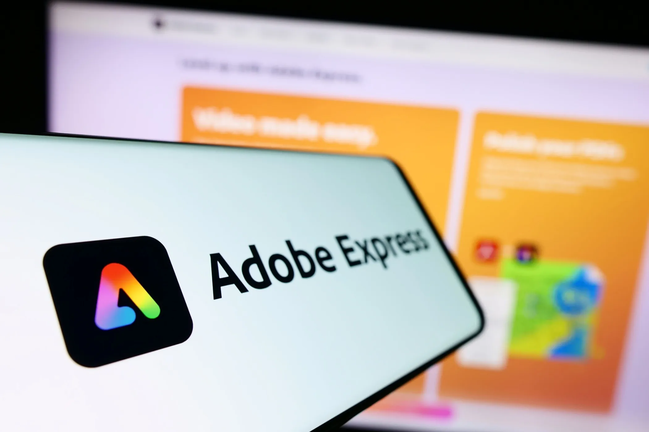 Adobe Express Logo on Smartphone, With Computer Design in Background