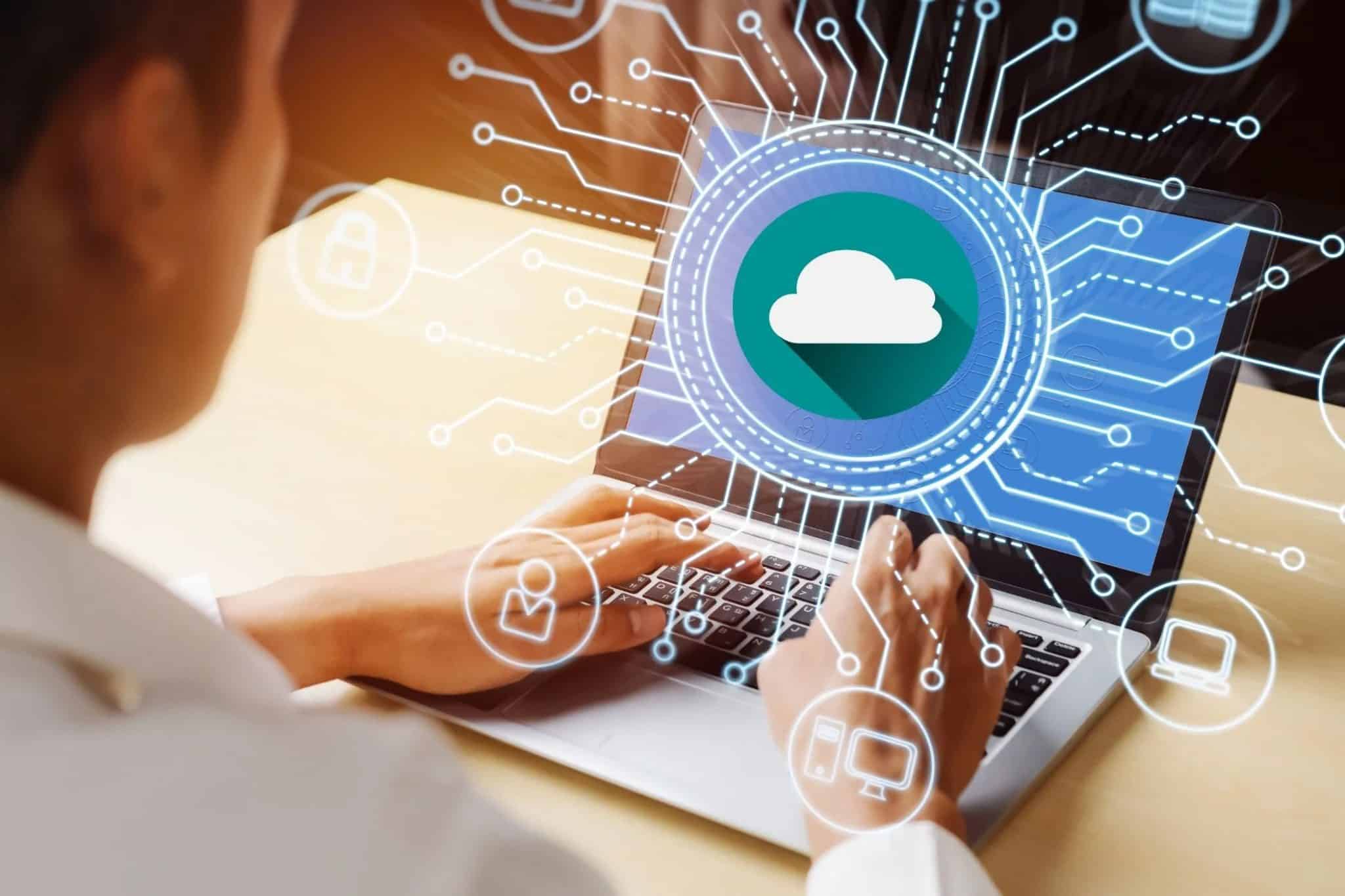 شخص يستخدم جهاز كمبيوتر محمول مع رسوم توضيحية للحوسبة السحابية مضافة في الأعلى