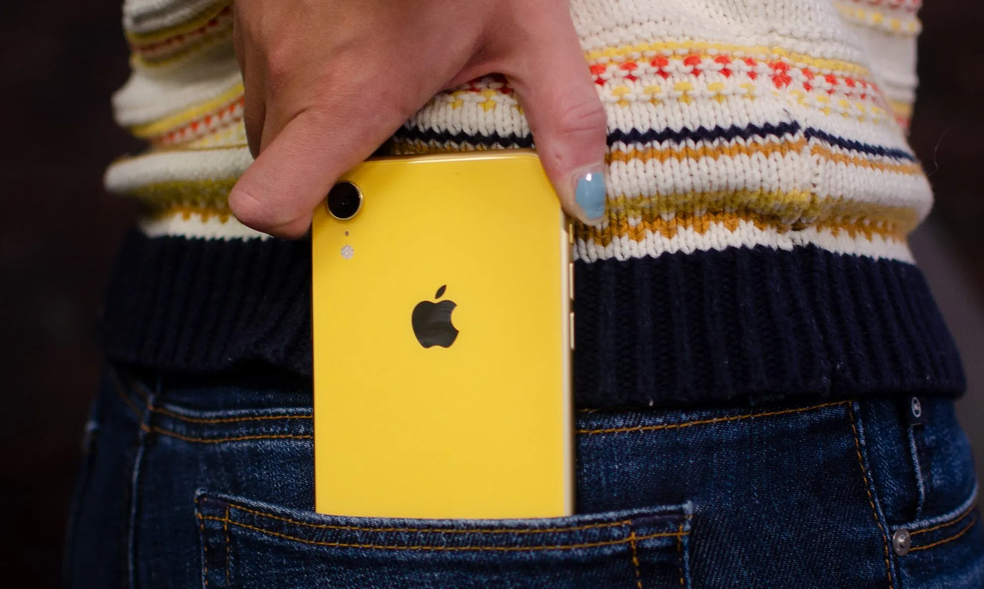 Person taking an iPhone out of their pocket.