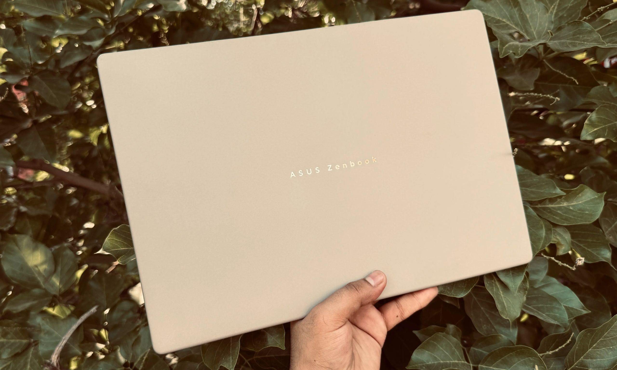 Person holding the Asus ZenBook A14 laptop in daylight.