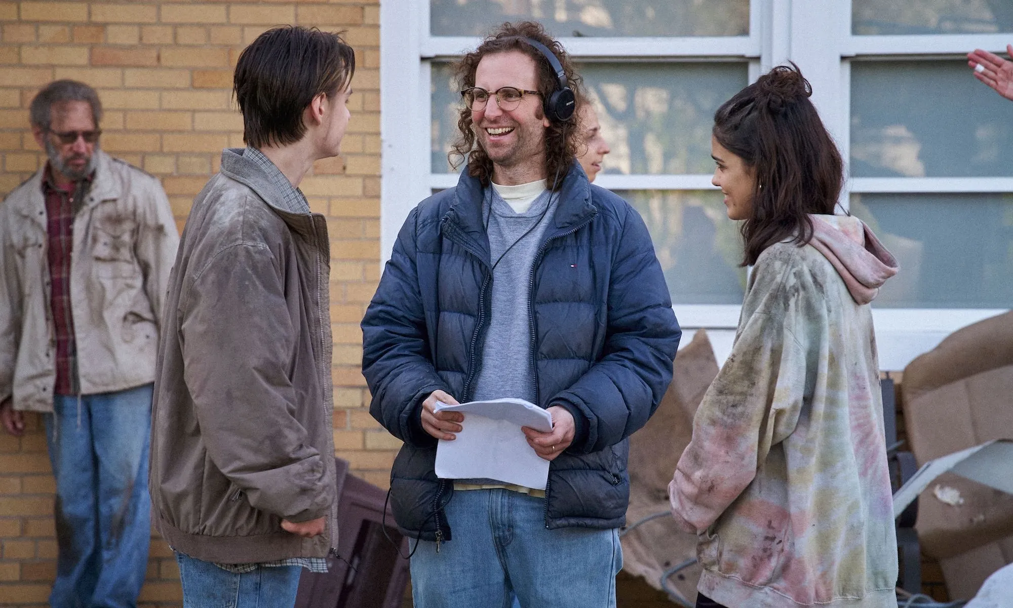 رجل يرتدي سماعات رأس يقف بين صبي وفتاة في Y2K.