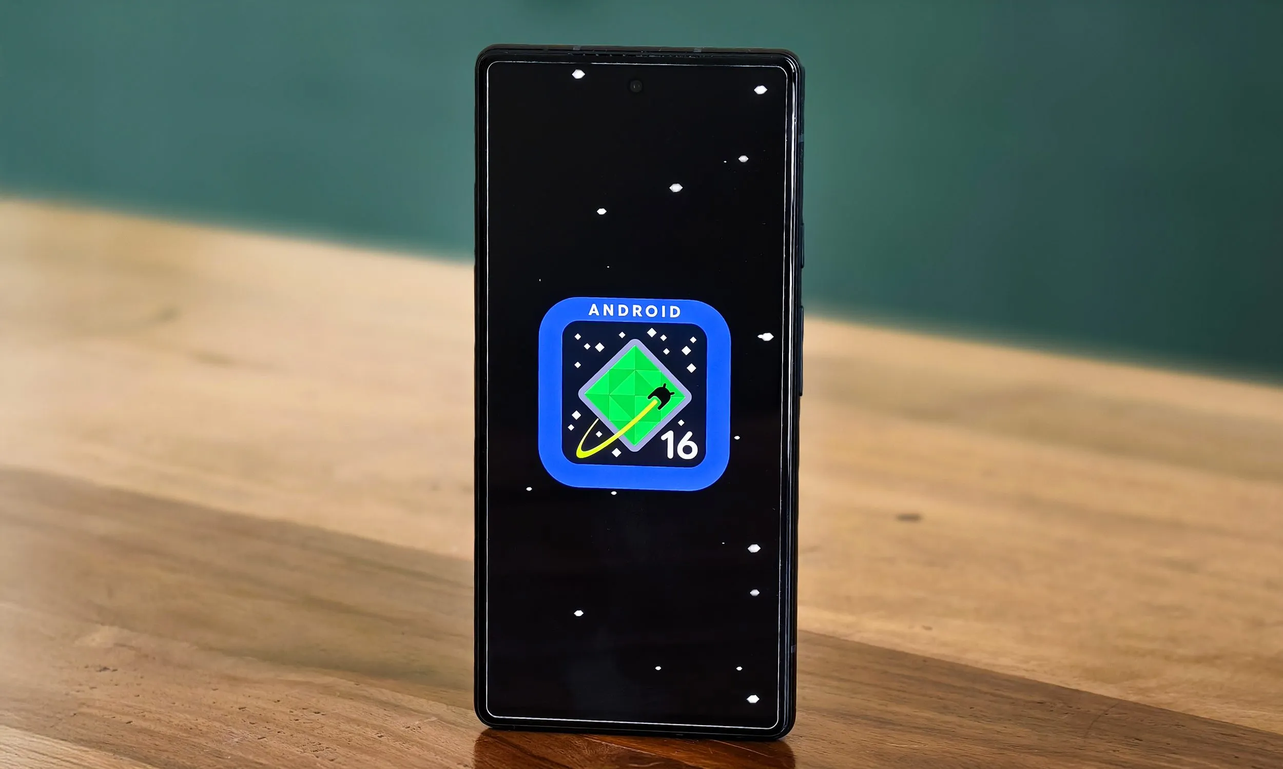 شعار Android 16 على Google Pixel 6a موضوع على طاولة.