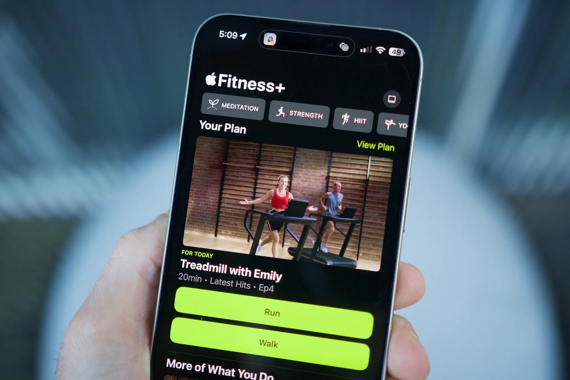 شخص يحمل جهاز iPhone مفتوحًا عليه تطبيق Apple Fitness، ويعرض ميزة الخطط المخصصة.